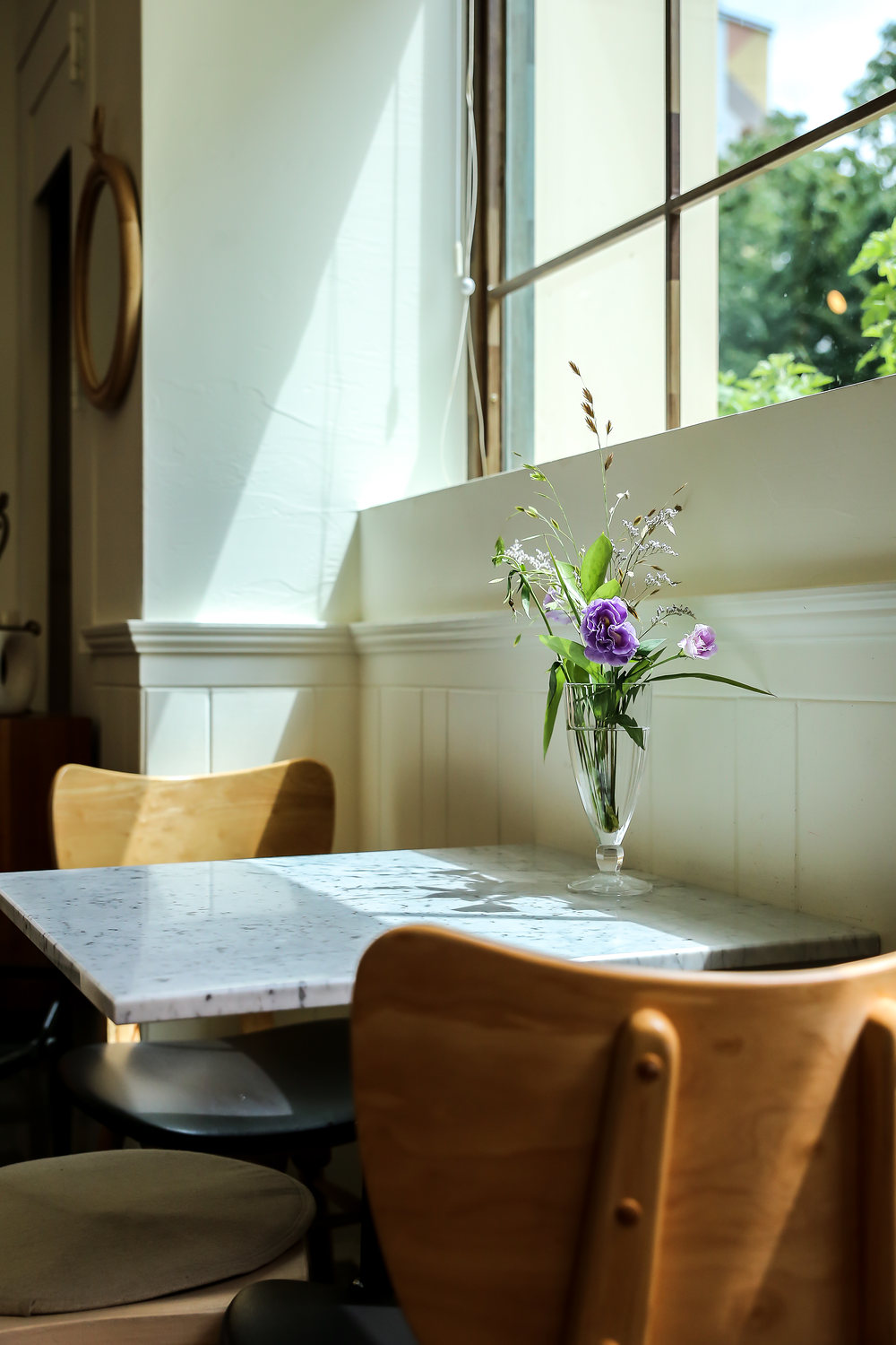 A marble table by the window, wildflowers in a glass.