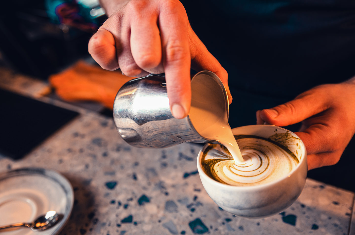 Pouring milk into a cup on the counter.