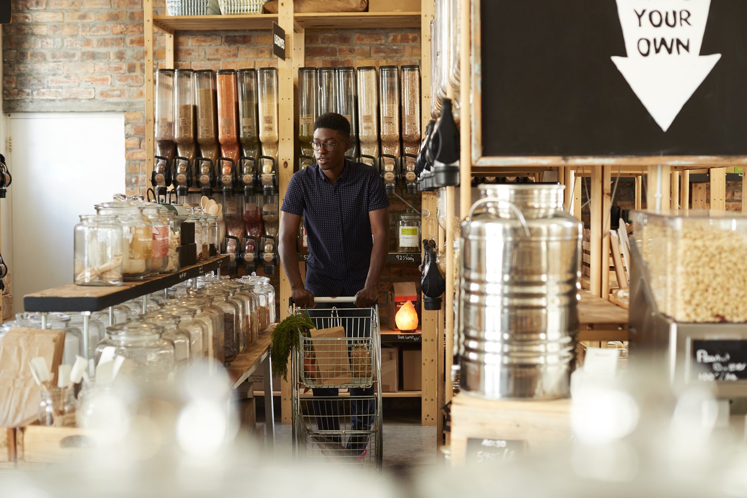 A customer pushing a trolley past the refill jars in a dried goods shop.