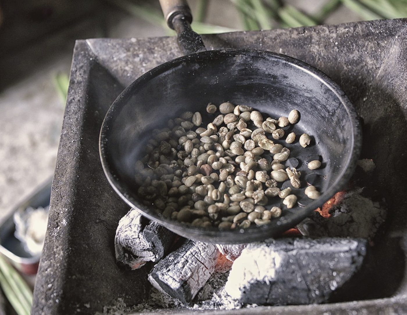 Green coffee roasting in a shallow pan.
